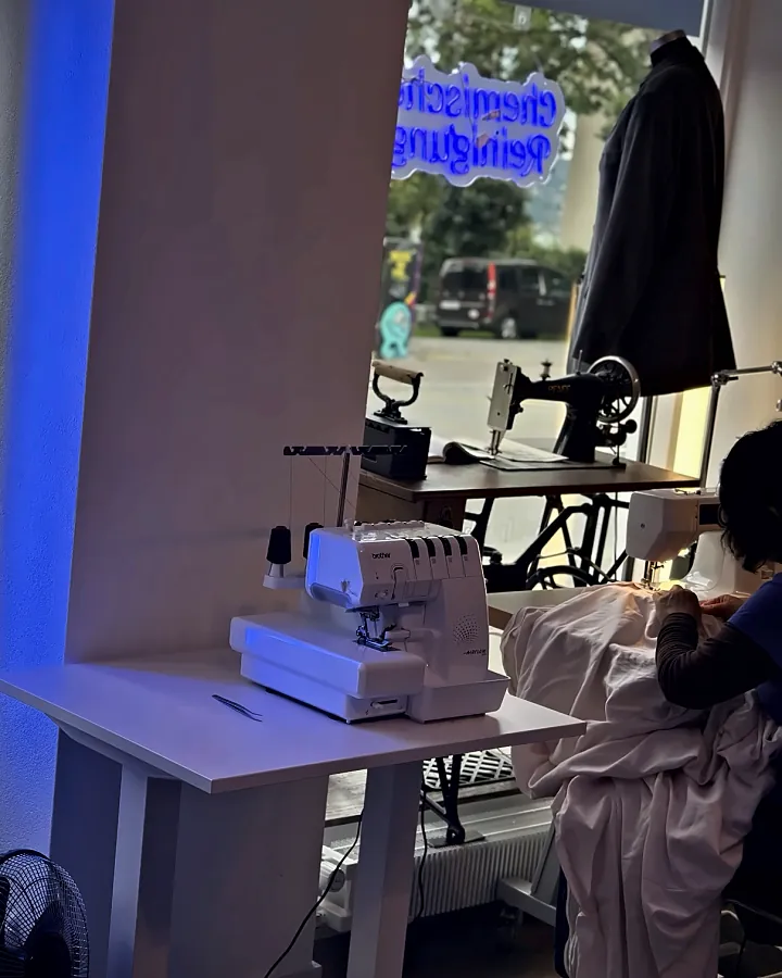 Eine Schneiderin bei der Arbeit an der Overlock-Maschine am Fenster